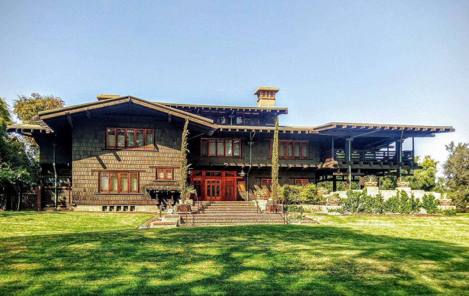 The Gamble House in Pasadena, a dark shingled Craftsman house with deep eaves above a lawn, a Wikimedia Commons photograph in the encyclopedia of Mike Kobeissi