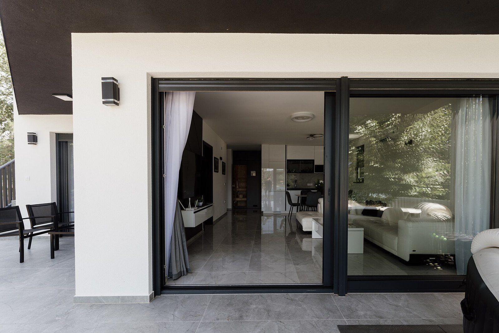 A modern house with wide sliding glass doors opening its living room onto a patio, a Wikimedia Commons photograph in the encyclopedia of Mike Kobeissi