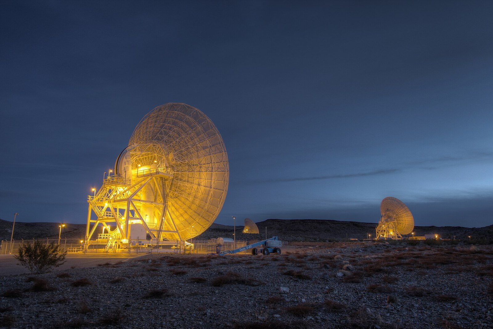 A large Deep Space Network dish antenna lit at dawn in the Apollo Valley at Goldstone in t, a Wikimedia Commons photograph in the encyclopedia of Mike Kobeissi